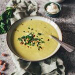 Erbsensuppe mit Minze und Crème fraîche in einer Schale, garniert mit Kräutern und Mandeln. | moeyskitchen.com
