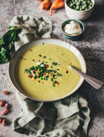 Erbsensuppe mit Minze und Crème fraîche in einer Schale, garniert mit Kräutern und Mandeln. | moeyskitchen.com