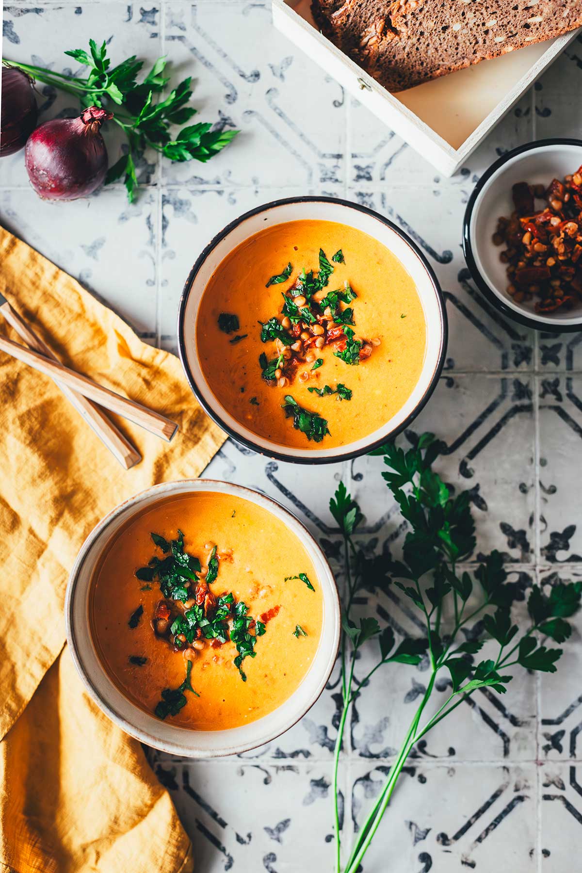 Tomaten-Linsen-Suppe mit Schmand, serviert mit frischen Kräutern und gehackten getrockneten Tomaten. | moeyskitchen.com