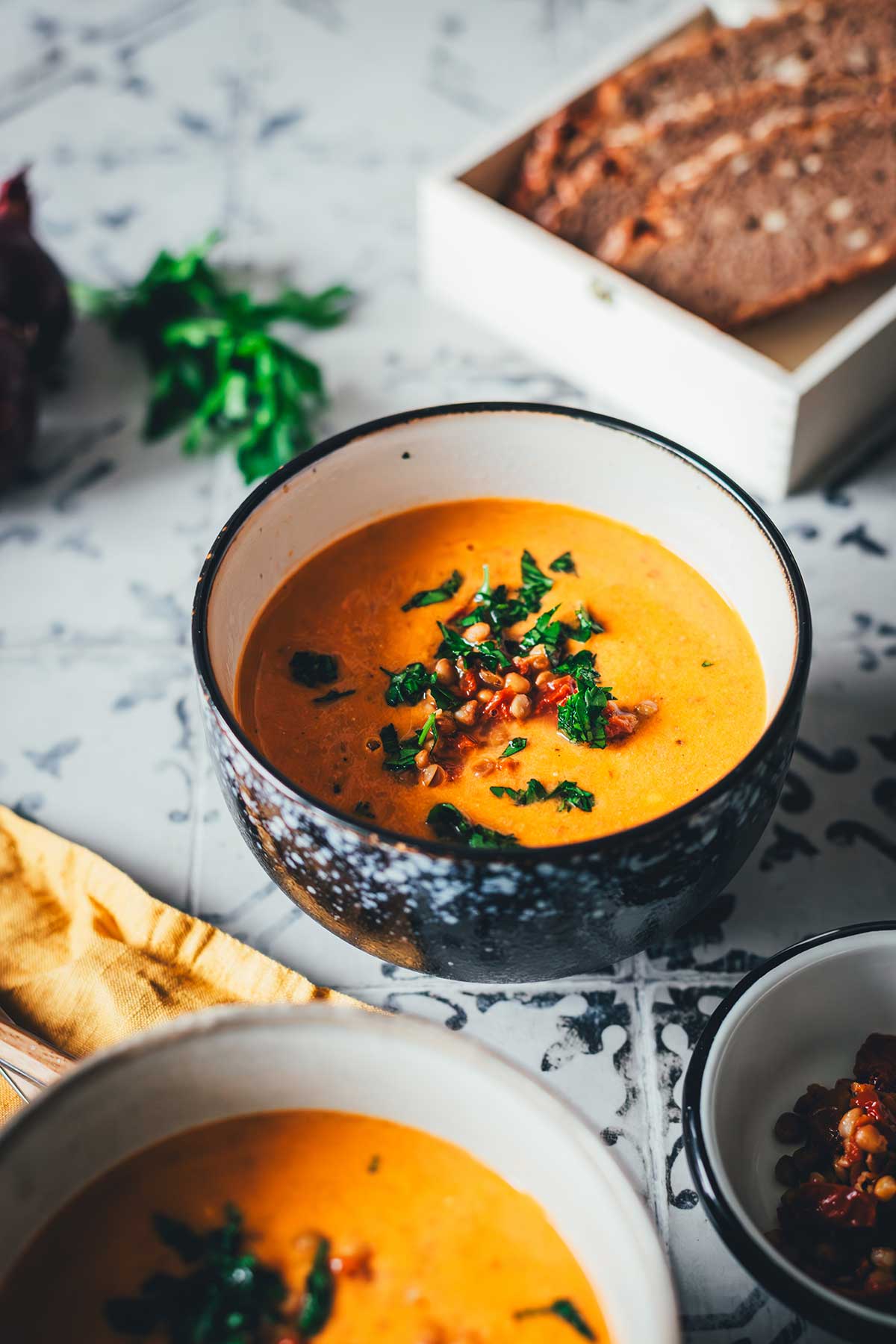Tomaten-Linsen-Suppe mit Schmand, serviert mit frischen Kräutern und gehackten getrockneten Tomaten. | moeyskitchen.com