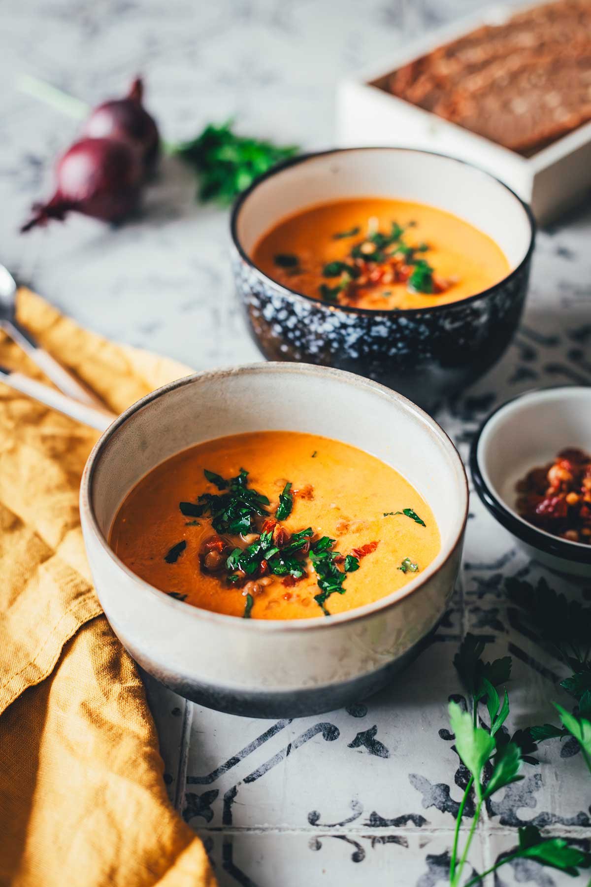 Tomaten-Linsen-Suppe mit Schmand, serviert mit frischen Kräutern und gehackten getrockneten Tomaten. | moeyskitchen.com