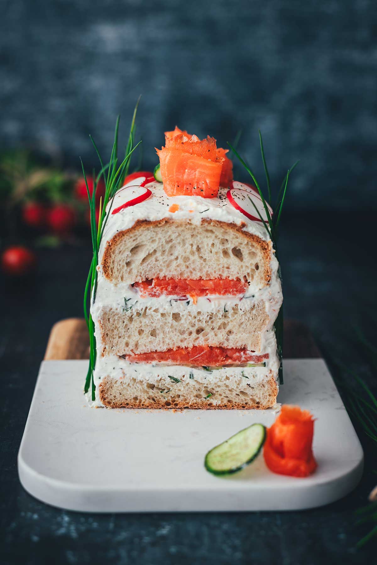 Frontale Draufsicht auf eine herrliche Brottorte. Man sieht den Anschnitt der Sandwichtorte mit Räucherlachs und Frischkäsecreme.