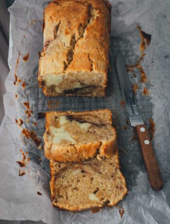 In Stücke geschnittener Apfel-Frischkäse-Kuchen auf Backpapier mit einem Messer | moeyskitchen.com