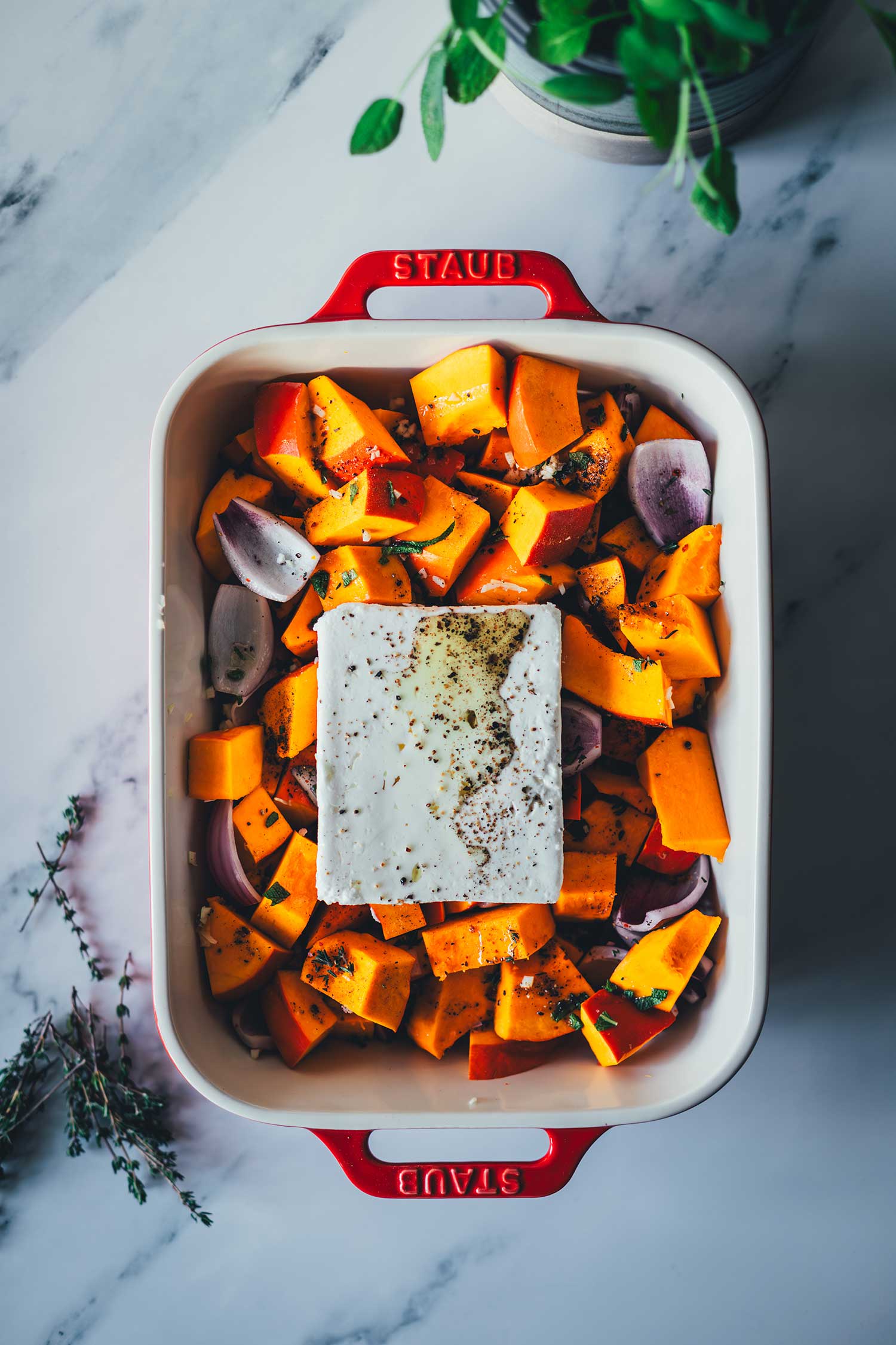 Topshot-Aufnahme der Zutaten für die Baked Feta Pasta – hier mit Kürbis und Feta in einer roten Auflaufform auf dem Weg in den Backofen | moeyskitchen.com