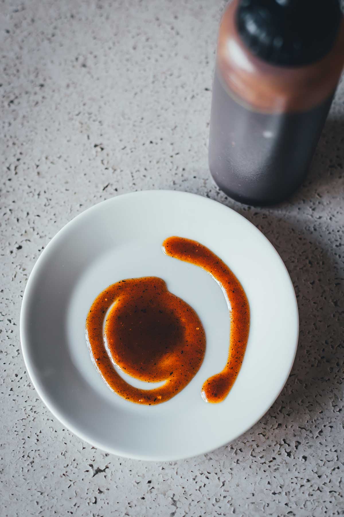 Ein kleiner weißer Teller als Topshot fotografiert, darauf sieht man die dunkle, karamellige Pumpkin Spice Sauce | moeyskitchen.com