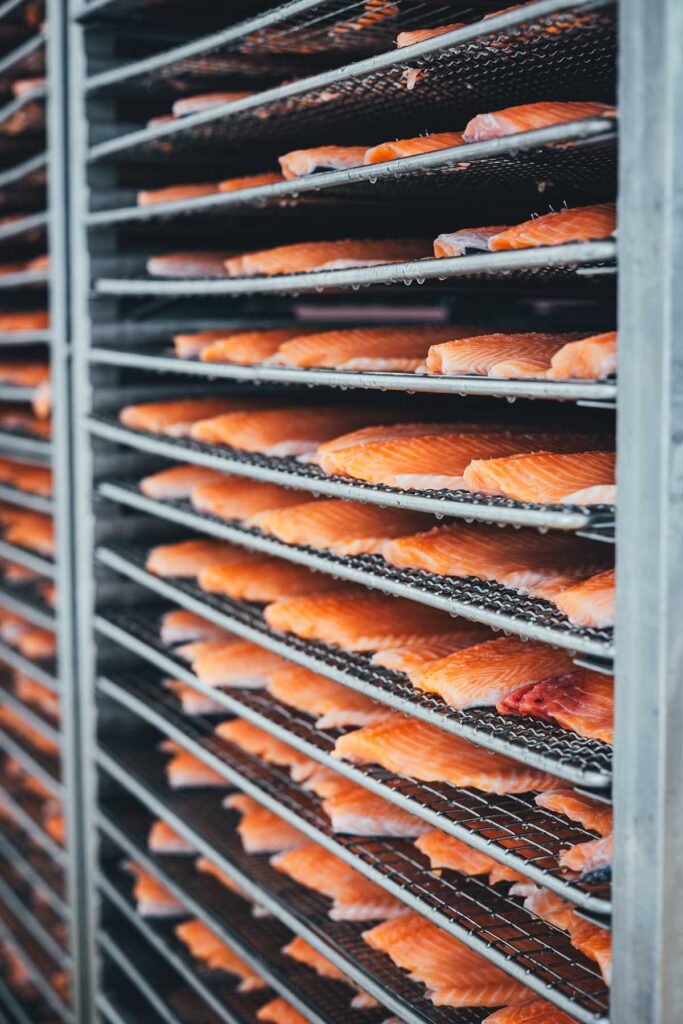 Wildlachs-Filets sauber aufgereiht in einem Räucherofen in einer Fischfabrik, Reportage | moeyskitchen.com