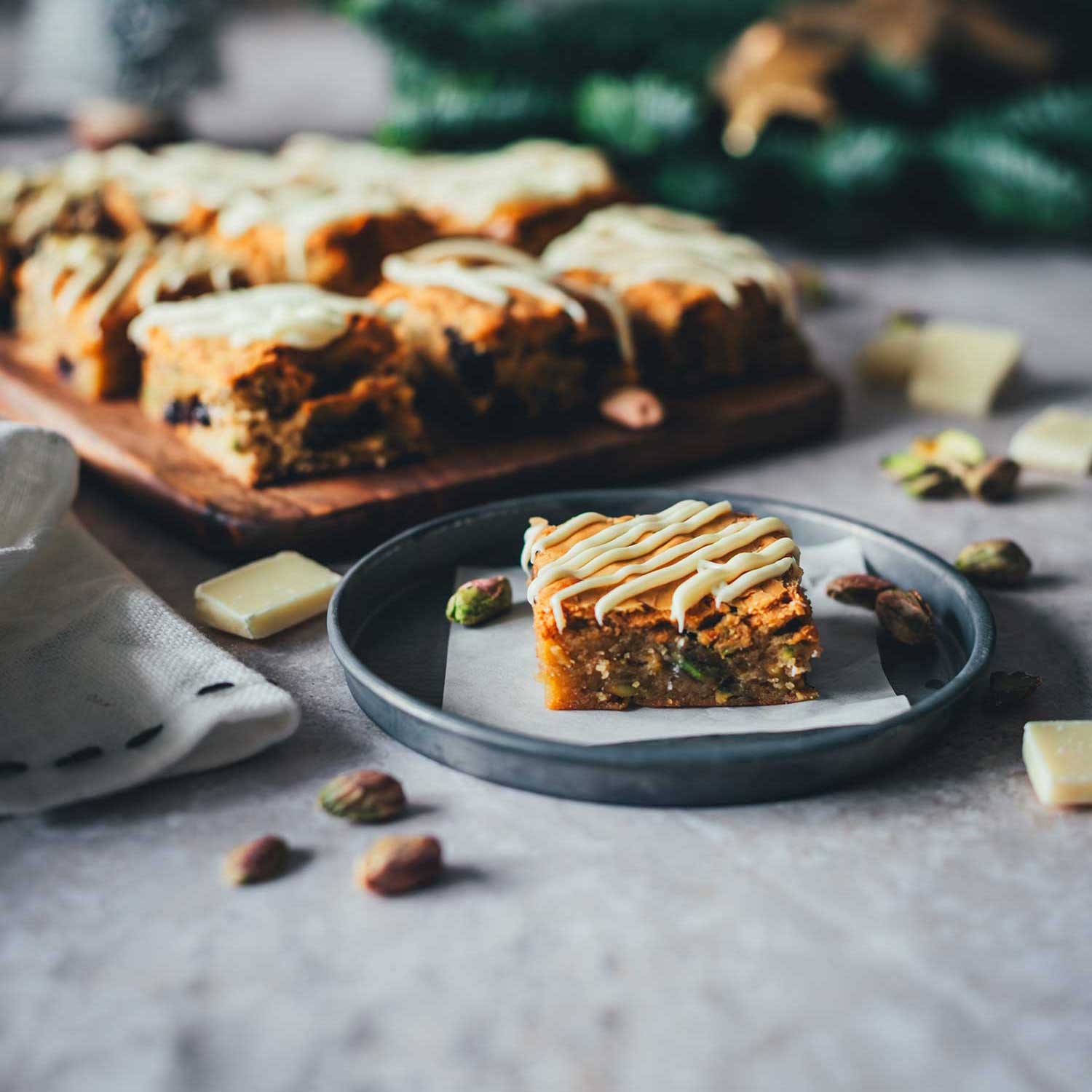 Seitliche Ansicht von Weihnachts-Blondies im weihnachtlichen Setting mit Tannenzweigen und Deko im Hintergrund.