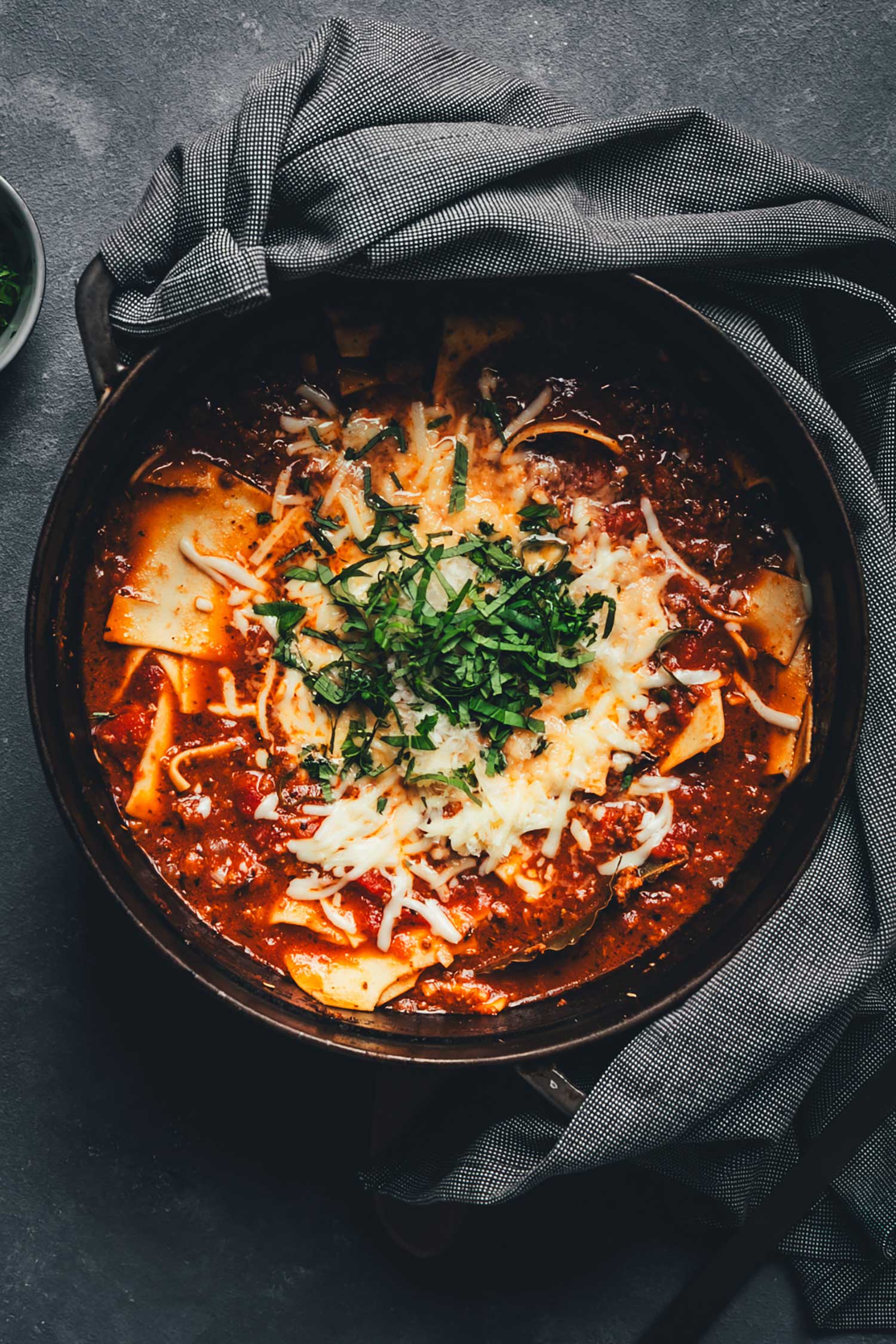 Deftige One Pot Lasagne-Suppe mit Rinderhack, Lasagneblättern, Tomatensauce und geschmolzenem Käse, serviert mit frischem Basilikum und Parmesan.