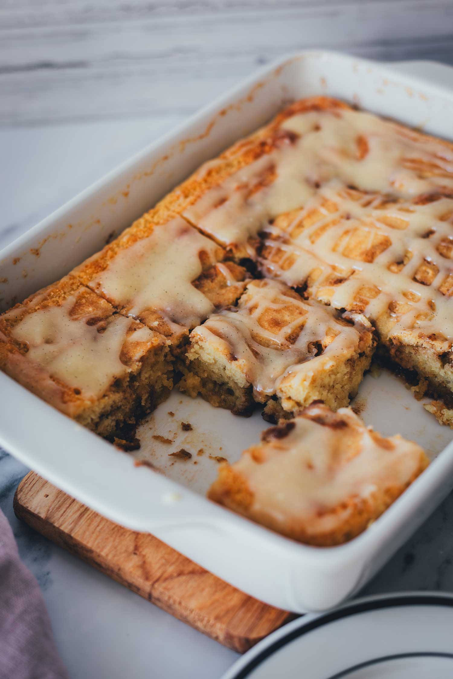 Seitliche Nahaufnahme vom Zimtschnecken-Kuchen ohne Hefe in der Backform - zwei Stücke wurden schon entnommen und man sieht den Anschnitt und die herrlich leichte Textur des Kuchens.