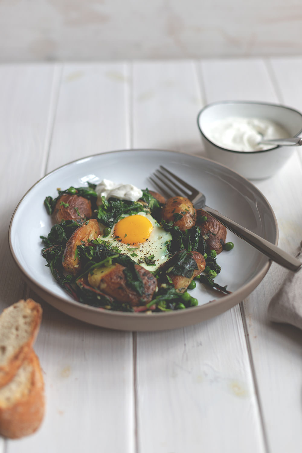 Grüne Shakshuka wird auf einem tiefen Teller und mit leckerem Dip serviert. Kartoffeln, Mangold, Spinat und Ei machen satt